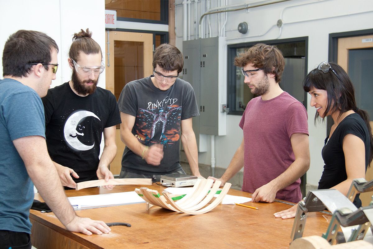 Un groupe d'étudiant qui travaillent autour d'une pièce de bois