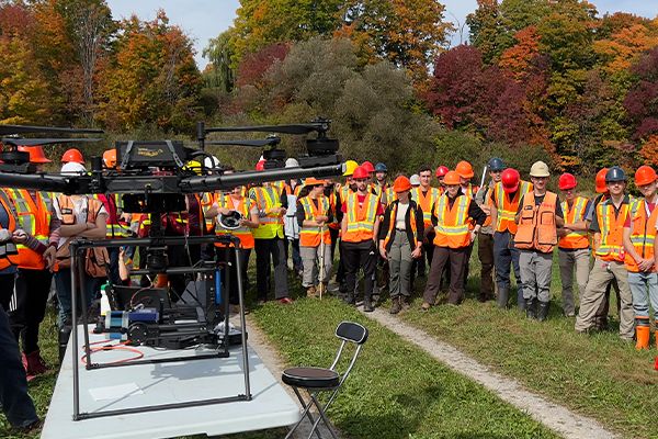 Groupe d'universitaires qui observe un drone dehors