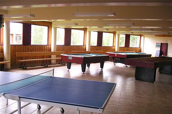 Salle avec des bancs, une table de ping pong et des tables de billard.