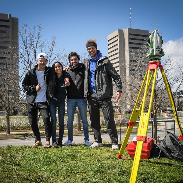 Quatre étudiants dehors devant un laser de prise de mesure extérieur