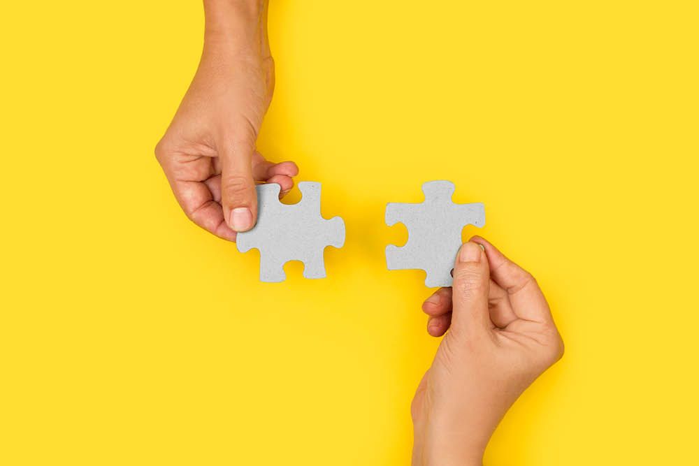 Deux mains tenant une pièce de puzzle