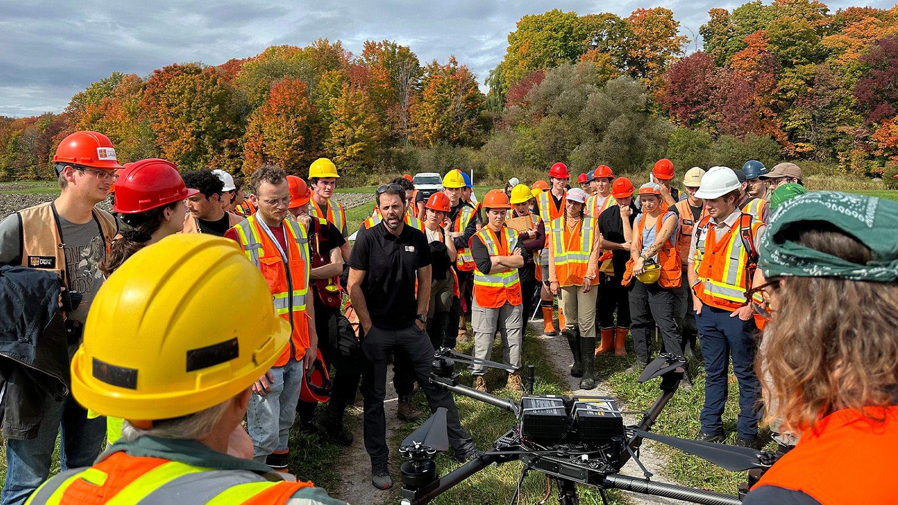 Enseignement Groupe d'étudiants avec un enseignant rassemblés autour d'un drone dehors en été