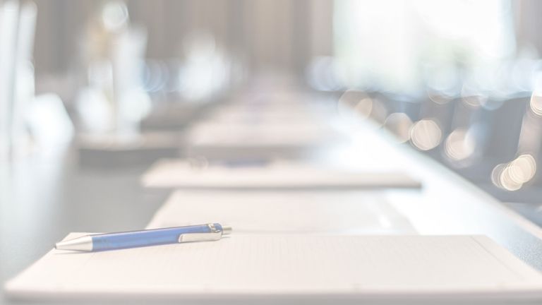 Un crayon et des papiers sont posés sur une table de réunion