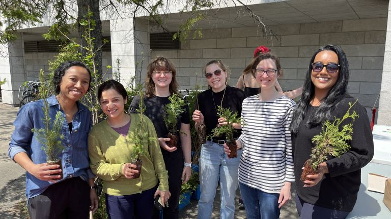 Groupe de personnes qui tiennent un petit plants d'arbre.
